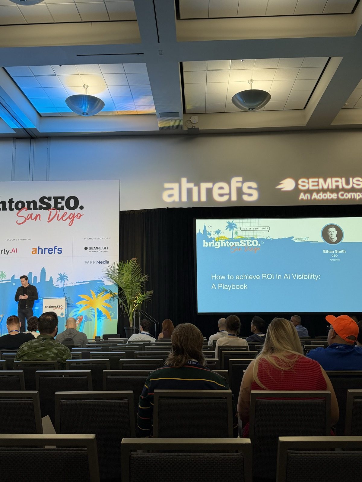 Escenario de brightonSEO San Diego con la slide de título 'How to achieve ROI in AI Visibility: A Playbook', Ethan Smith, CEO, Graphite.